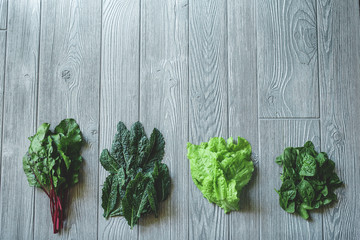 Mixed Greens including Kale, Spinach, Lettuce, and Beet Greens over a wooden table.