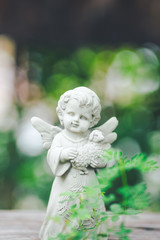 Cupid sculpture in garden,background is blurred bokeh.