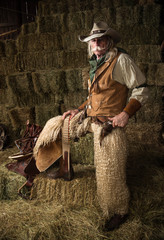 Old west cowboy with woolie chaps, pistols, vest and cowboy hat full length portrait