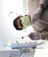 Professional dentist with green mask and tools and latex gloves