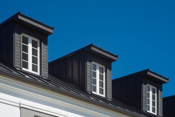 Top of residential house facade against blue sky