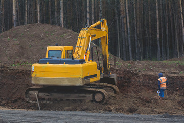 Construction of the highway - yellow excavator at work