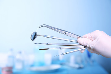 Dentist holding set of medical tools on blurred background