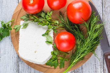 White cheese, knife, parsley, tomatoes on a wooden boards background