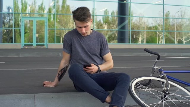 Man sitting on the border and typing a scrolling websites slow motion