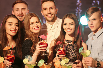 Friends with tasty cocktails at party in night club
