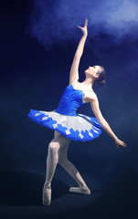 Young beautiful ballerina on dark background