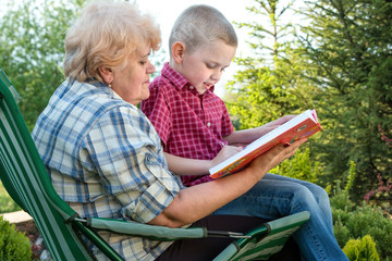 Grandmother and grandson reading a book outdoors.Family holiday with my grandmother.