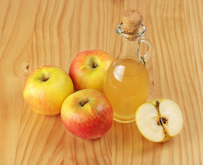 Apple cider vinegar and fresh apple on a wooden background