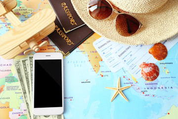 Composition with smartphone, money, passports and tickets on world map background