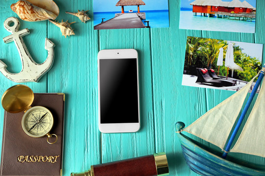 Smartphone and travel planning accessories on wooden background