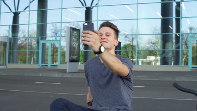 Young man sitting on the border and making a selfie slow motion