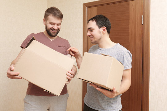 Gay couple unpacking cardboard boxes at home
