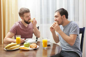 Obraz na płótnie Canvas Happy gay couple having breakfast in kitchen