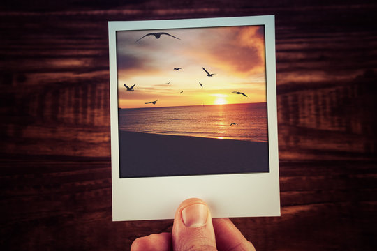 Polaroid postcard of beautiful sunset over ocean coastline with bird silhouettes and clouds. Travel memories scrapbooking template with copy space