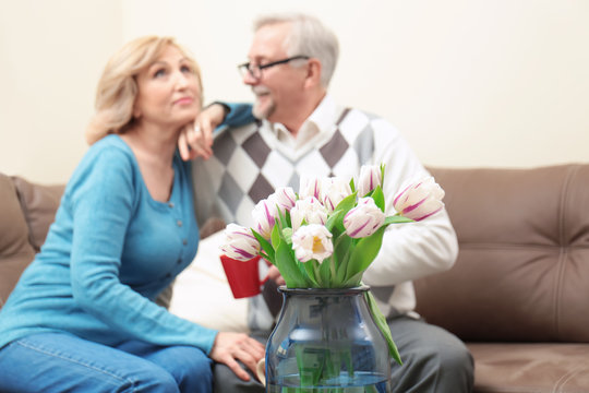 Bouquet of tulips and blurred elderly couple on background