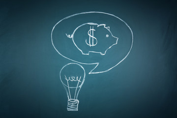 Chalk drawing of piggy bank and light bulb on board