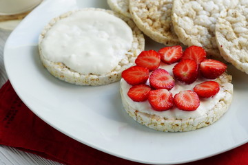 Breakfast for health sandwiches from rice vegan waffle with Greek yogurt and fresh strawberries on a white red background