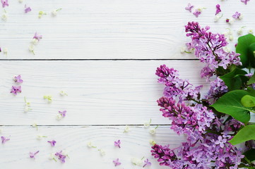 Fototapeta premium Pattern of a branch of lilac and other spring flowers on a white wooden background. top view. flat lay. Holiday concept. Copy space
