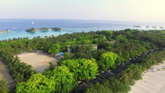 AERIAL: Amazing sandy beach and turquoise water in exotic Maldives over a green tropical forest