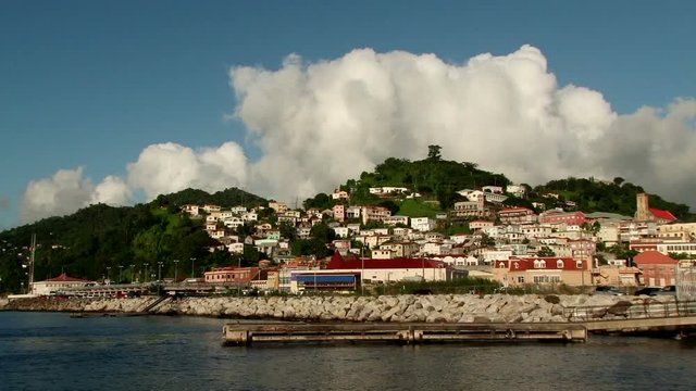 Wide view of town and white dramatic clouds over hill of St George’s town in Grenada