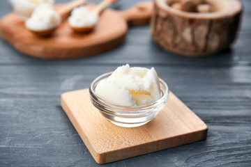 Shea butter in bowl on wooden background