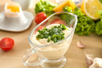 Delicious mayonnaise in gravy boat on kitchen table