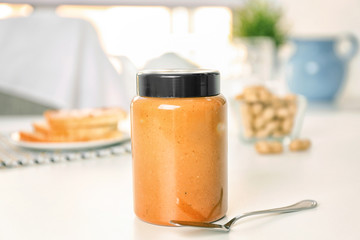 Delicious peanut butter in jar on kitchen table