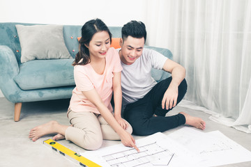 Attractive young asian adult couple looking at house plans.