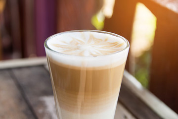 hot coffee latte art with glass on wooden table.