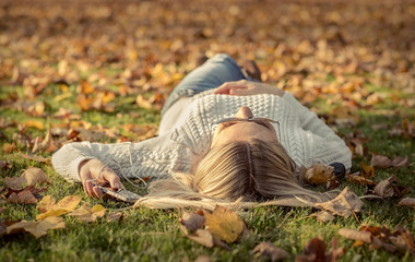 Woman listening music on grass at autumn time