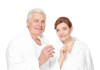 Senior couple with toothbrushes on white background