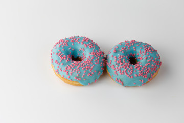 Donuts with blue glaze and pink sprinkles isolated on white background. Top view.