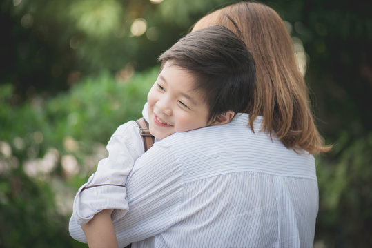 asian mother hugging with her son in the park