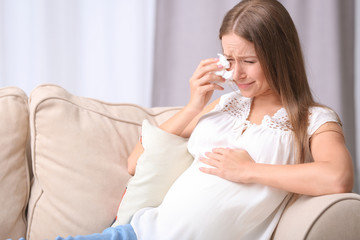Emotional pregnant woman crying at home