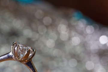 Solitaire diamond ring on silver sparkle background