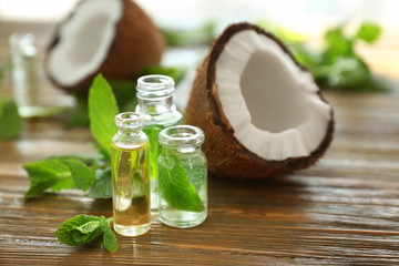 Beautiful composition with perfume bottles, mint and coconut on wooden background