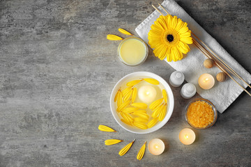Beautiful spa composition of flower petals with water in bowl and candles on color background