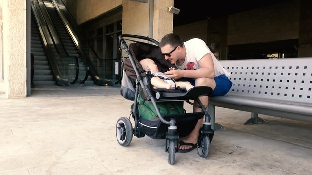 Man is fastening child to a stroller at station
