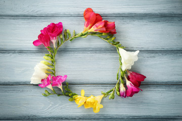 Frame made of beautiful freesia flowers on wooden background