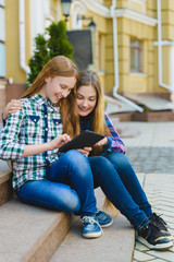 Fototapeta na wymiar smiling teenage girls with tablet pc computer outdoors