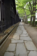 山居倉庫 ／ 東北地方の米どころ、山形県庄内のシンボル「山居倉庫」の風景です。山居倉庫は明治26年(1893)に建てられ、現在も現役の米保管倉庫です。白壁、土蔵づくり９棟からなる倉庫の米の収容能力は10,800トン(18万俵)です。夏の高温防止のために背後にケヤキ並木を配し、内部の湿気防止には二重屋根にするなど、自然を利用した先人の知恵が生かされた低温倉庫です。