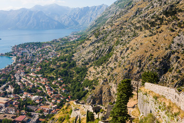 Fototapeta na wymiar Looking over the Bay of Kotor in Montenegro with view of mountains, boats and old houses with red tile roofs, fortress