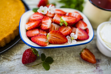 Fresh strawberries and delicious sponge cake on a wooden background.