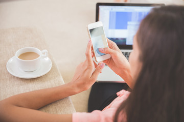 busy woman at home using mobile phone and laptop at the same tim