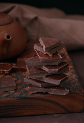 Pieces of dark chocolate on a wooden board at monochrome setting.