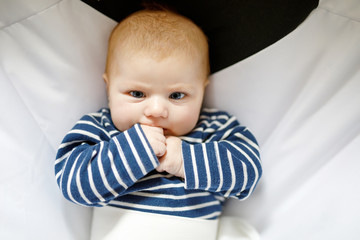 Cute adorable two months baby sucking fist.