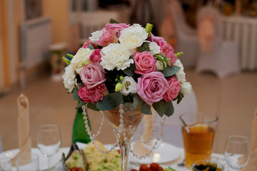 wedding arrangement in a tall glass in white and pink tones. Composed of carnations and roses.Wedding decoration