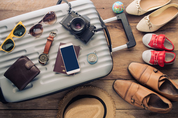 Obraz na płótnie Canvas Clothing traveler's Passport, wallet, glasses, smart phone devices, on a wooden floor in the luggage ready to travel with family