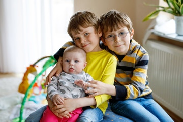 Two little happy kid boys with newborn baby girl, cute sister.
